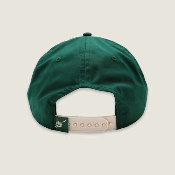 The back view of a dark green baseball cap with a beige adjustable strap and a small embroidered logo on the side, set against a solid light beige background.